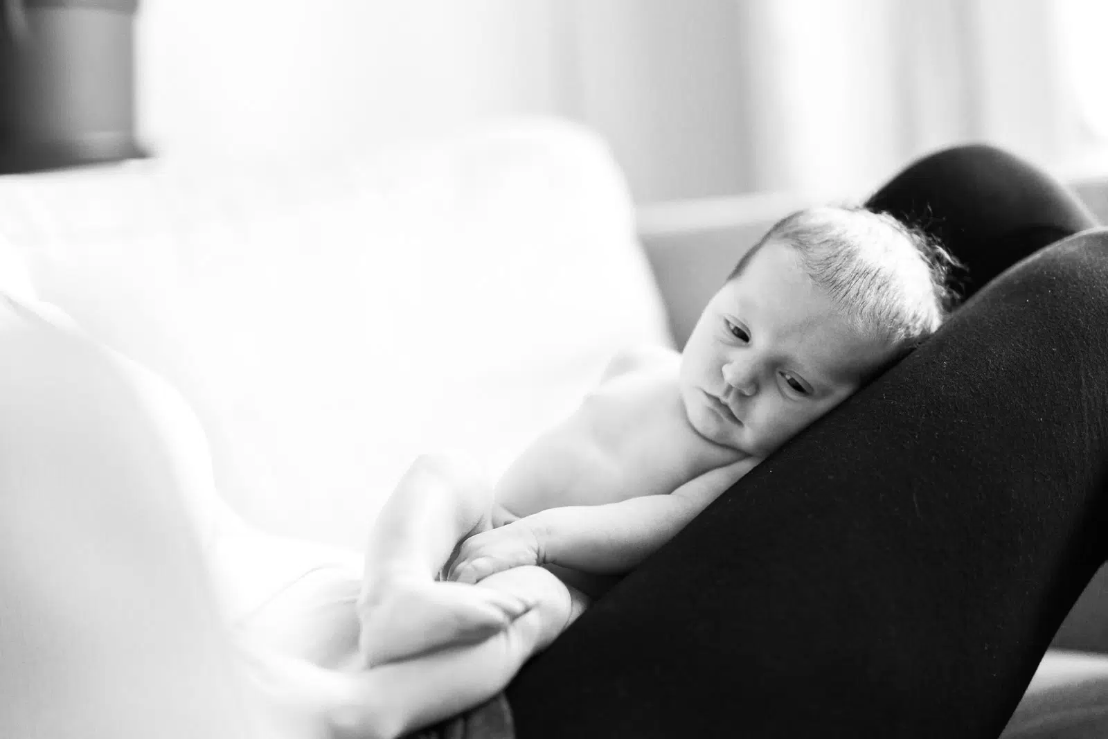 Foto eines Babys, das auf den Beinen eines Erwachsenen liegt