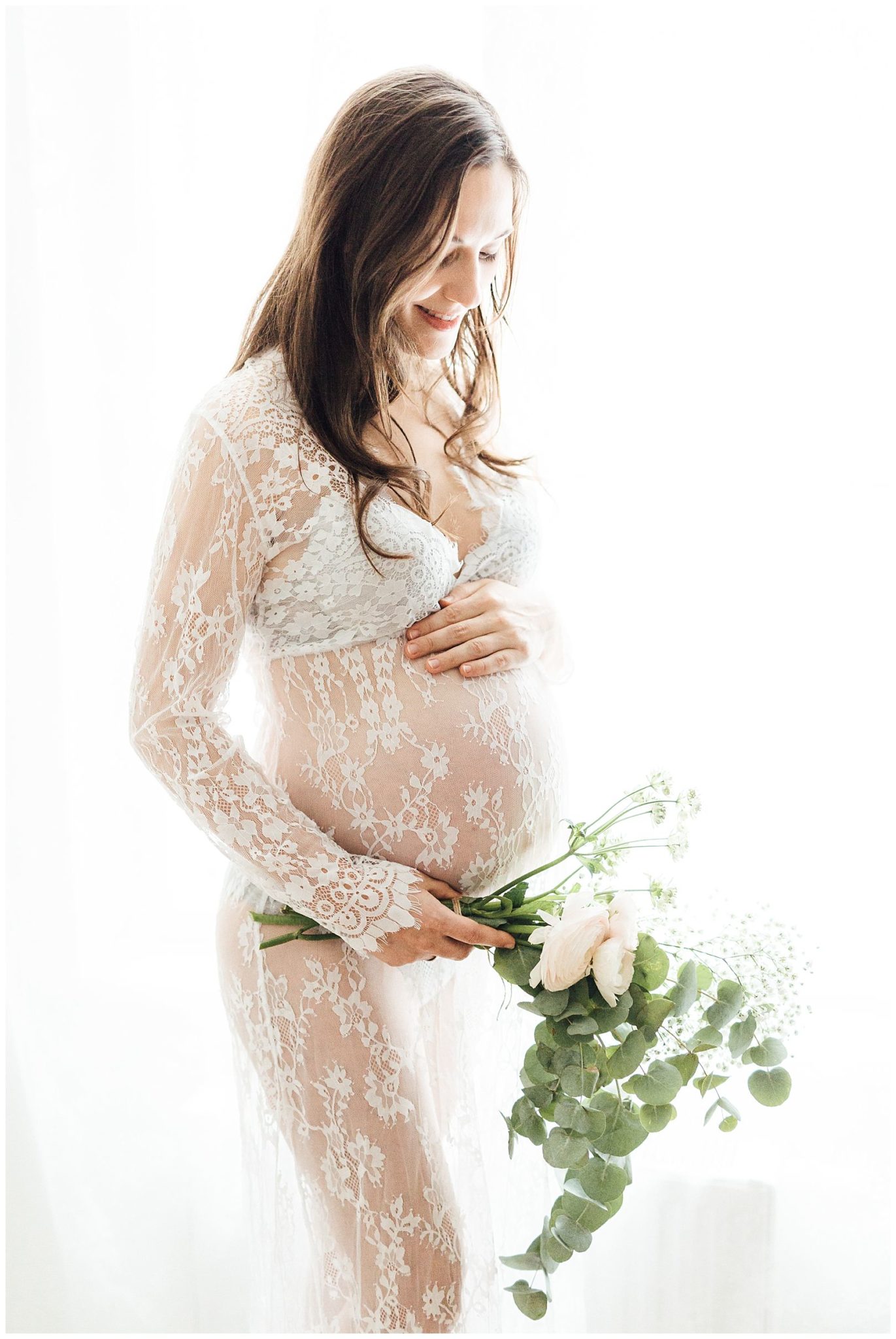 Eine schwangere Frau im Spitzenkleid mit Blumenstrauß