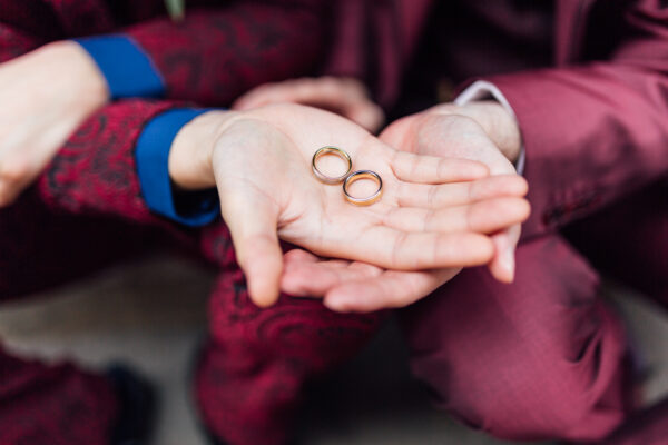 Zwei Hände halten Eheringe einer gleichgeschlechtlichen Regenbogenhochzeit