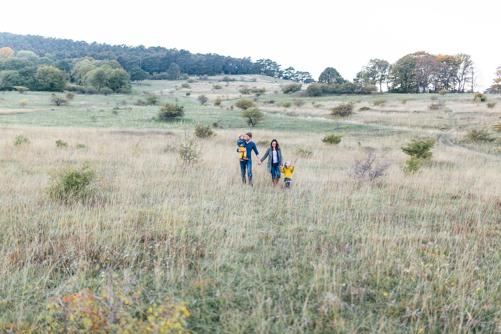 Familienfoto im Herbst mit einer Familie mit zwei Kindern in weiter Landschaft