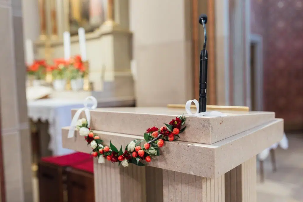 Blumendeko an einem Rednerpult in einer Kirche
