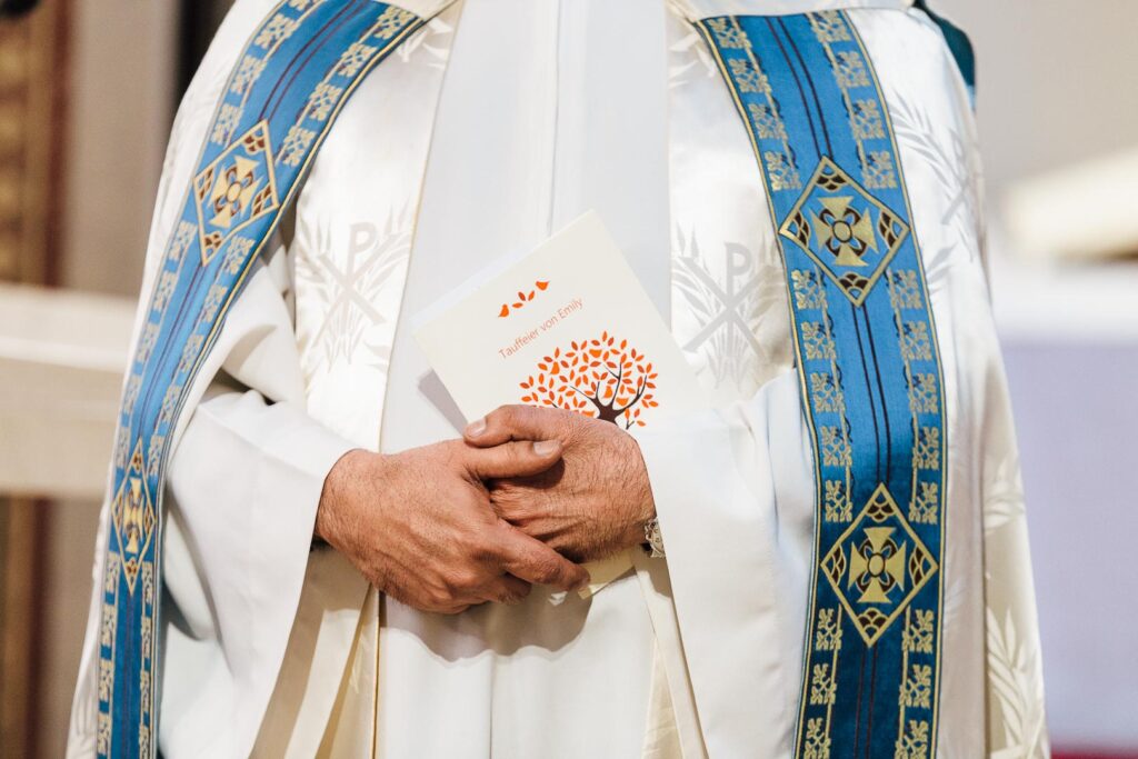 Hände und Umhang eines Pfarrers eine Karte haltend