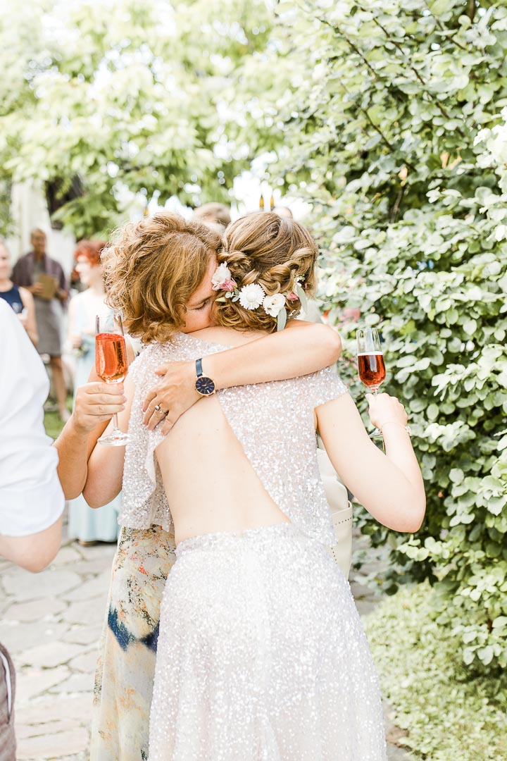 Eine Frau umarmt eine Frau in elegantem Brautkleid emotional