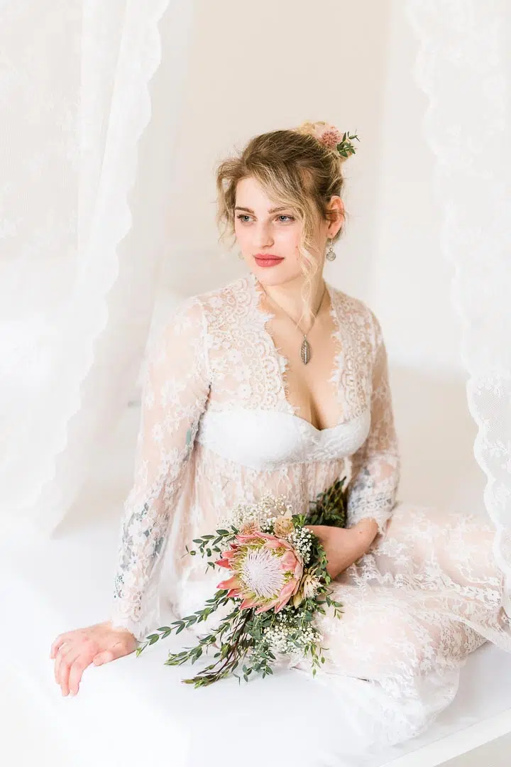 Verträumtes Portrait einer Frau im Spitzenkleid mit Blumen