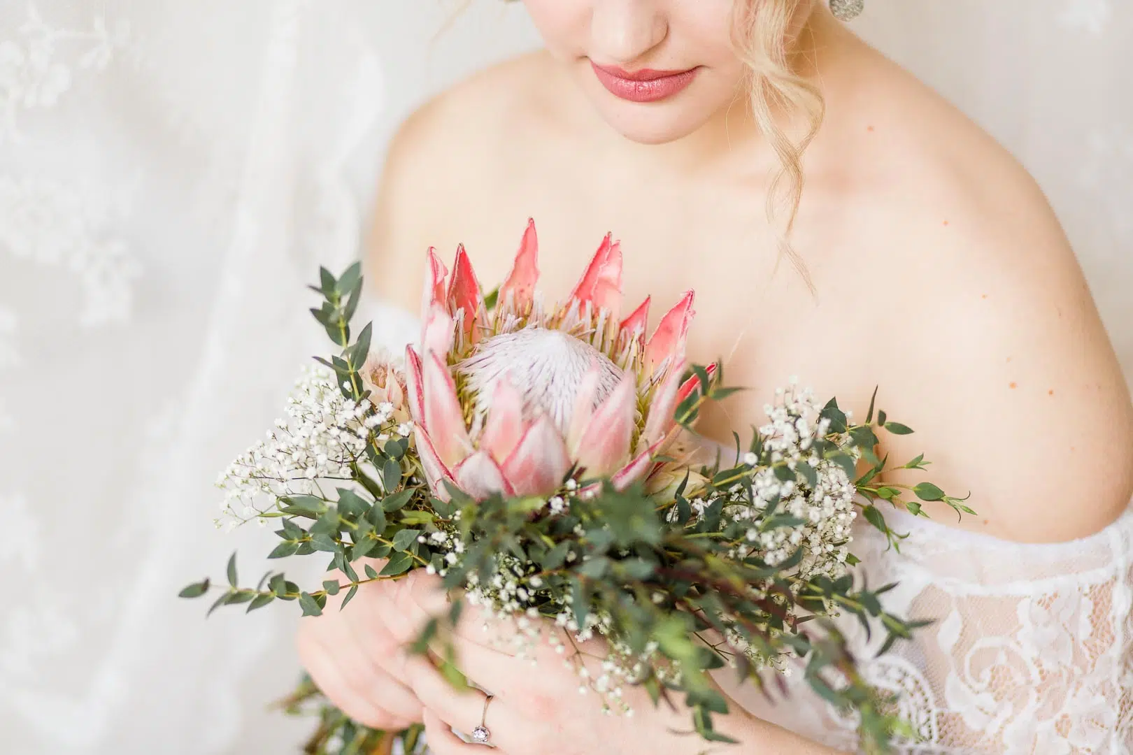 Halbportrait einer Frau mit Spitzenkleid und Protea