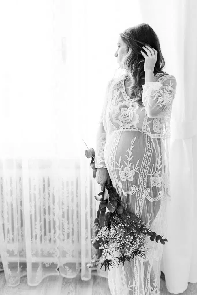 Boudoirfoto einer schwangeren Frau am Fenster