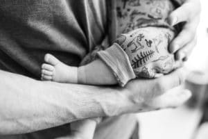 Fuß eines Babys auf dem nackten Unterarm eines Mannes