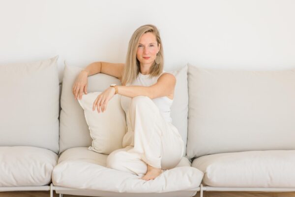 Eine Frau in heller Keidung sitzt auf einem Sofa