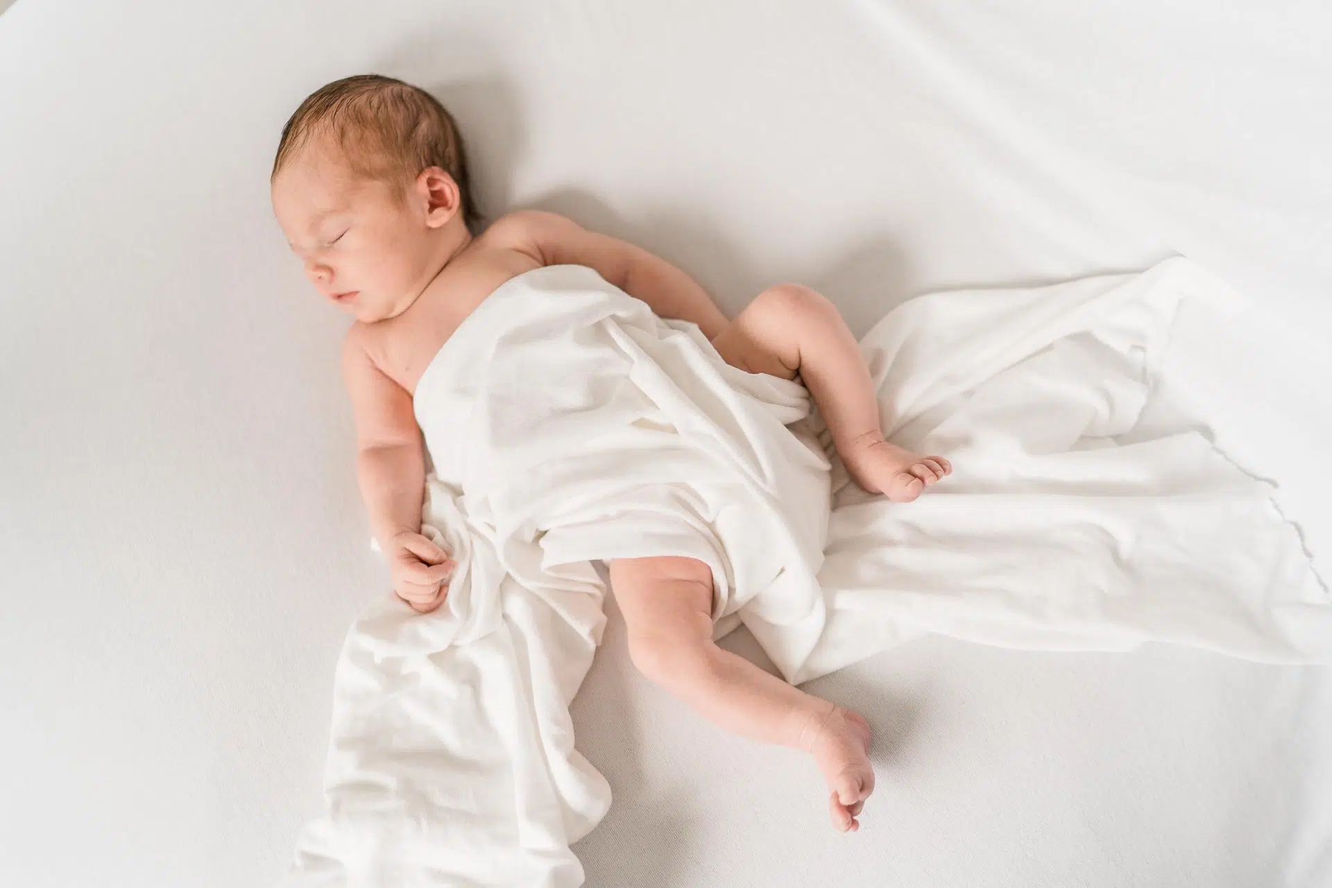 Gutschein-für-frischgebackene-Eltern- Carmen-Trappenberg-Fotografie-4 Ein schlafendes Baby unter einer weißen Decke