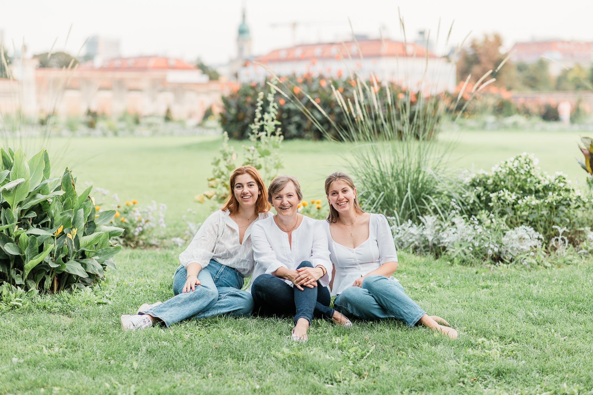 Drei Frauen sitzen lachend auf einer Wiese im Wiener Augarten