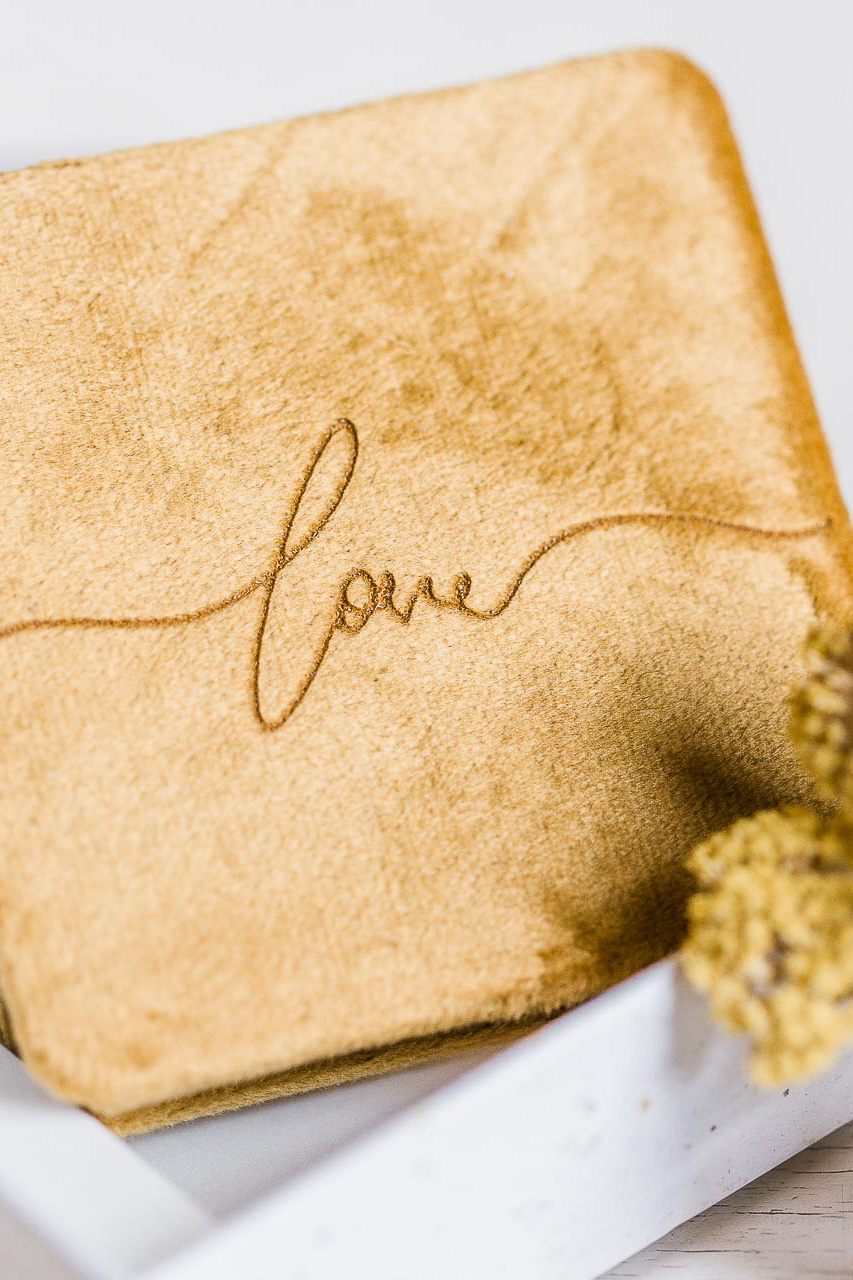 Nahaufnahme eines edlen Fotoprodukts zur Präsentation von profesionellen Familienfotos in gelbem Samteinband mit der Aufschrift love
